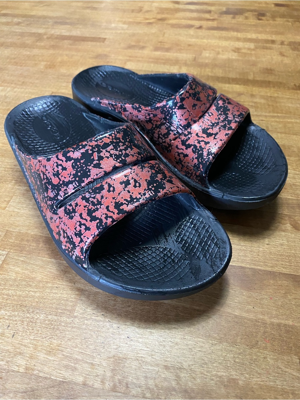 OOFOS Kids Slide Sandals in Black and Red/orange Speckle splash